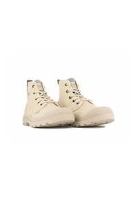 Stivaletti alla caviglia in tela beige con punta tonda, lacci piatti e suole in gomma texture. Presentano un colletto imbottito e un accento con logo sulla linguetta.