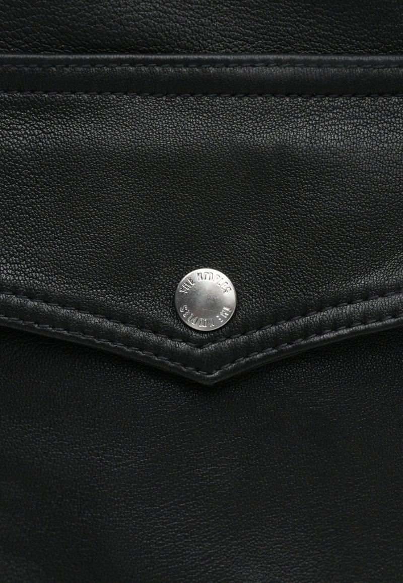 Black leather wallet featuring a silver snap button, textured surface, and contrasting stitching along the edges.