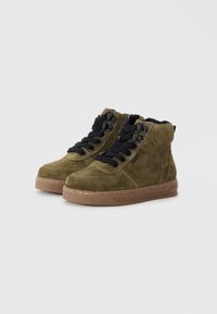 Bottes à cheville en daim vert avec des lacets et œillets noirs, dotées d'un col rembourré et d'une semelle en caoutchouc marron avec des détails texturés.