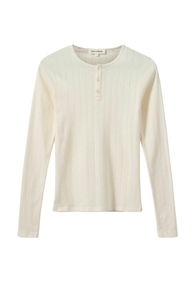 Hosszú ujjú krémszínű felső bordázott anyagból, texturált levélmintával. Kerek nyakkivágással és három gombbal rendelkezik elöl.