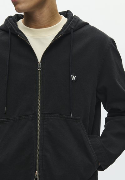 Sweat à capuche noir à zip en coton, doté d'une grande poche kangourou, d'une capuche avec cordon de serrage ajustable et d'un petit écusson logo sur la poitrine.