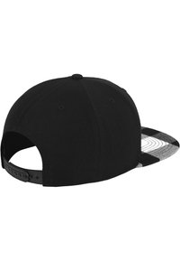 Sort cap med en struktureret sort krop og en ternet skygge i sort og hvid. Justerbar rem bagpå til tilpasning af størrelse.