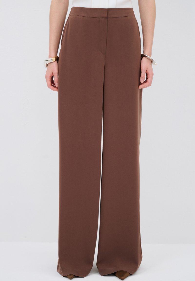 Bruine wijde broek van een gladde stof. Heeft een op maat gemaakte taille en geen zichtbare zakken, met een schone, vloeiende silhoutte.