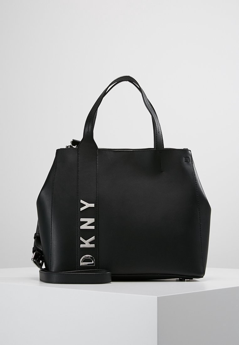 Czarna torebka wykonana z materiału syntetycznego, o wyraźnej strukturze, z krótkimi uchwytami oraz odpinanym paskiem na ramię z srebrnym logo DKNY.