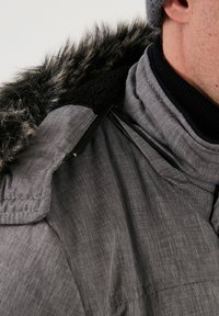 Jachetă exterioară gri, cu glugă din blană artificială, material texturat, căptușeală neagră și detalii cu fermoar în zona gâtului.