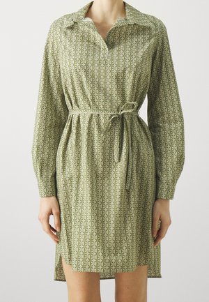 Jasnozielona sukienka koszulowa za kolano z długimi rękawami, małym ciemnozielonym geometrycznym wzorem, kołnierzykiem, rozcięciami po bokach i paskiem do wiązania w talii.