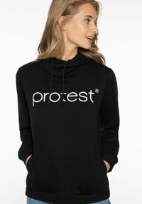 Sudadera negra con capucha ajustable y un gran logo blanco "pro:test" en el frente. Cuenta con un corte relajado y bolsillo tipo canguro.