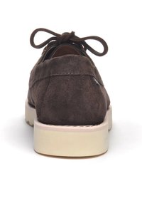 Scarpa in suede marrone con suola piatta color crema, caratterizzata da una punta arrotondata e chiusura con lacci, con cuciture visibili e una superficie liscia.