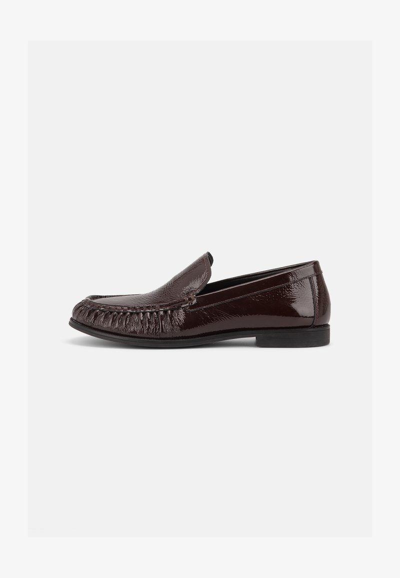 Mocassin en cuir marron foncé brillant avec coutures moc toe, petit talon et design slip-on sur fond blanc uni.