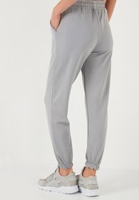 Hellgraue Jogginghosen mit elastischem Taillenbund und Bündchen, ausgestattet mit Seitentaschen und einem glatten, strukturierten Stoff.