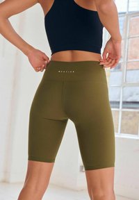 Shorts da bicicletta verde oliva, a coste, con vita alta. Presentano un logo sul retro e una superficie liscia. Ideali per l'abbigliamento sportivo.