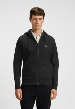 Black zip-up hoodie made of soft fabric with a front zipper, adjustable drawstring hood, and a small logo on the chest. Smooth texture.