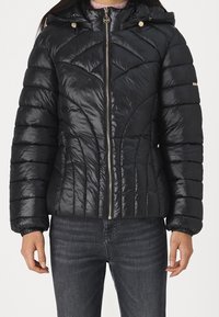 Giacca a vento nera con design a rombi trapuntato, materiale nylon lucido, chiusura con zip e due tasche con zip. Caratterizzata da un cappuccio e polsini elasticizzati.