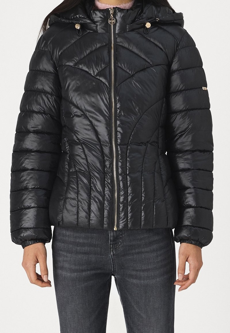 Giacca a vento nera con design a rombi trapuntato, materiale nylon lucido, chiusura con zip e due tasche con zip. Caratterizzata da un cappuccio e polsini elasticizzati.