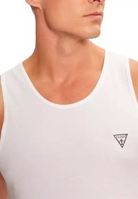 Witte katoenen tanktop met een ronde hals, voorzien van een klein zwart driehoekig logo op de linkerborst. Gladde textuur, eenvoudig ontwerp.