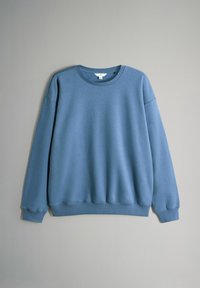 Maglione girocollo blu con maniche lunghe e polsini e orlo a costine, appeso su uno sfondo grigio chiaro uniforme.