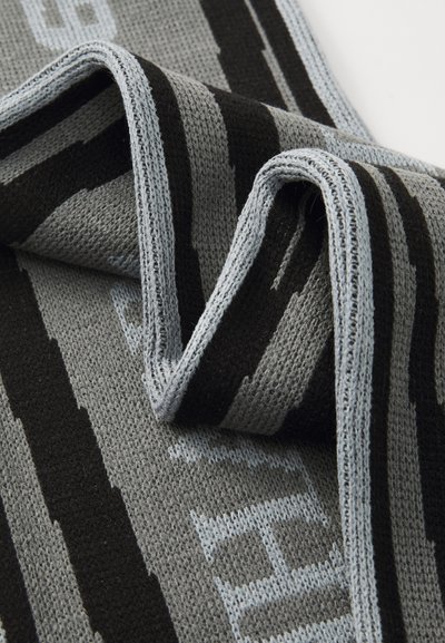 Szürke, fekete és világoskék színű kötött sál, vízszintes csíkokkal és texturált anyaggal. Az élek világoskék díszítéssel vannak ellátva.