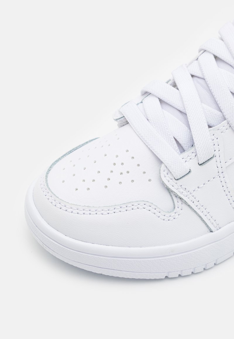 Zapatilla de cuero blanca con cordones planos blancos, puntera perforada y detalles grises en los laterales y el talón. Suela de goma.