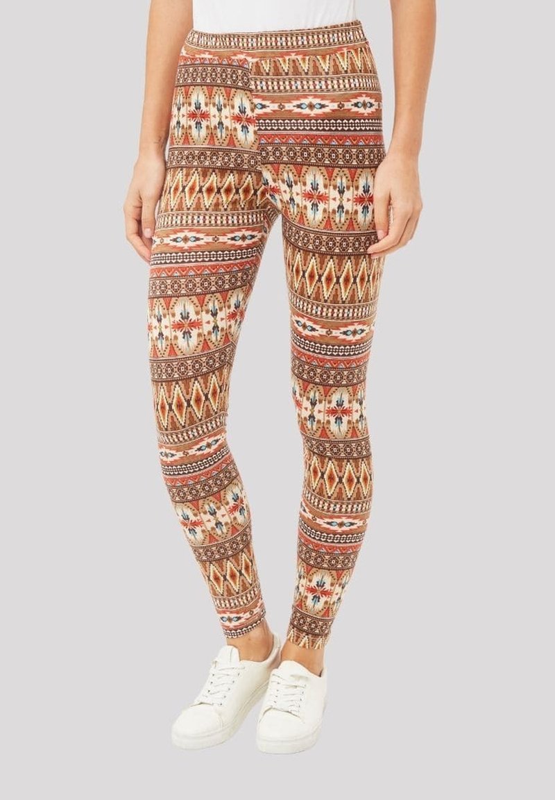 Leggings con estampado que presentan una mezcla de diseños geométricos en tonos tierra, con una tela elástica y una cinturilla alta. Combinados con zapatillas blancas.