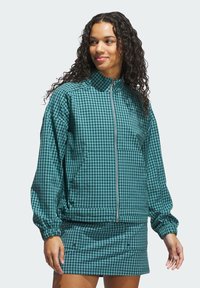 Grøn og sort ternet zip-up jakke med høj krave, elastiske manchetter og frontlommer; kombineret med en matchende mini-skirt.