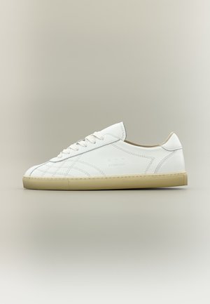 Witte lage leren sneaker met beige zool, vetersluiting en subtiele gestikte patronen op een neutrale achtergrond.