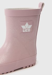 Ροζ ελαστική μπότα βροχής με γυαλιστερή φινέτσα, διαθέτει λευκό λογότυπο και υφασμάτινη σό�λα για πρόσφυση. Ρυθμιζόμενο επάνω μέρος με υφασμάτινη επένδυση.