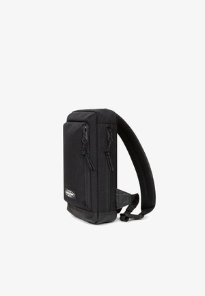 Sort stof rygsæk med to frontlynlåse, polstret ryg og justerbar rem. Glat tekstur, rektangulær form med en solid bund.