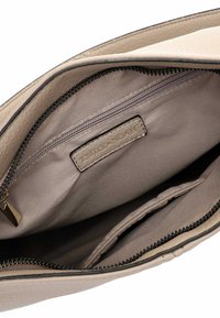 Beige leren handtas interieur met een ritsvak, gladde stofvoering en een labelpatch. Beschikt over een ritssluiting en twee open compartimenten.
