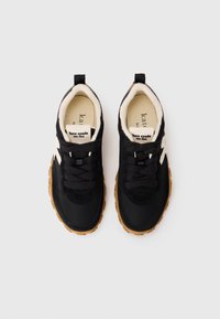 Black sneakers with a fabric and suede upper, cream lining, and brown rubber sole. Features rounded toe, laces, and logo tags on the tongue.
