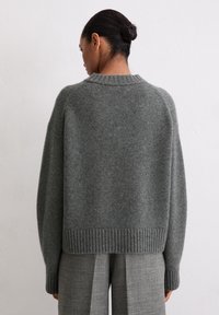 Grauer gestrickter Pullover mit einem gerippten Saum und Bündchen, mit lockerer Passform und Rundhalsausschnitt, von hinten gezeigt.