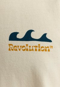 Beige katoenen stof met blauwe golfgrafieken boven de tekst "Revolutie" in oranje en gele letters. Soepele textuur, casual ontwerp.