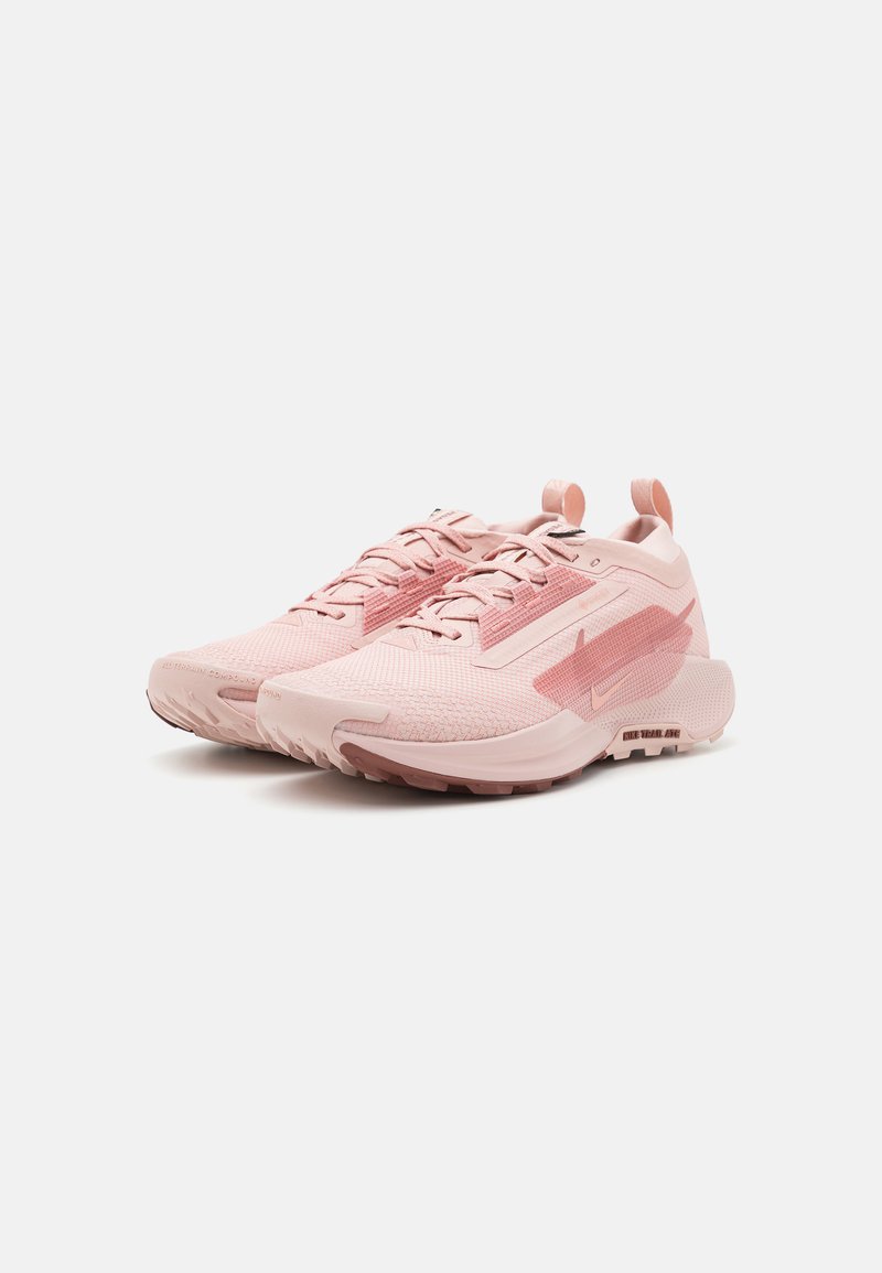 Zapatillas deportivas de color rosa claro con parte superior de malla, detalles texturizados y suelas de goma. Cuentan con un diseño de soporte y un sistema de cordones.