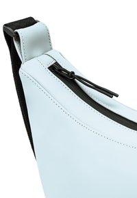 Borsa in materiale sintetico bianco con design curvo, dotata di una cerniera nera e di una tracolla con dettagli di cucitura. Texture liscia, forma compatta.