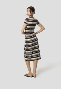 Sukienka midi w paski w kolorach granatowym, beżowym i białym. Dopasowany fason z krótkimi rękawami i okrągłym dekoltem, wykonana z gładkiej tkaniny.