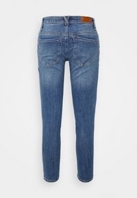Modré denimové slim-fit džíny zobrazené zezadu s dvěma zadními kapsami a hnědou koženou nášivkou na pasu.