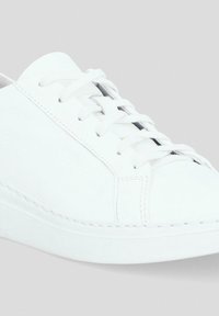 Białe skórzane trampki z gładką fakturą, okrągłym noskiem, sznurowanym przodem i płaską gumową podeszwą z detalami w postaci szwów.