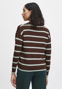 Pull en tricot rayé marron et menthe, à coupe décontractée, avec des manches longues et des poignets côtelés, des détails de couture visibles et un col rond.