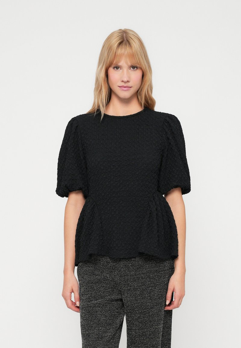 Top peplum preto texturizado com mangas curtas e bufantes, decote redondo e um ajuste descontraído. Combinado com calças estampadas.