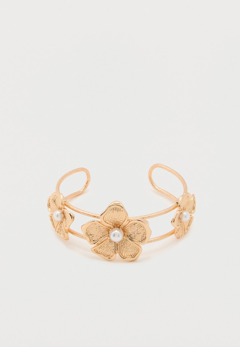 Χρυσό βραχιόλι-μανσέτα με τρία υφασμένα σχεδιαστικά λουλούδια, το καθένα διακοσμημένο με μια κεντρική λευκή πέρλα, σε απλό λευκό φόντο.