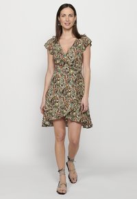 Bloemenwrapjurk met korte gerimpelde mouwen, een getailleerde taille en een uitlopende rok. Het meerkleurige patroon bevat groene, oranje en bruine tinten.