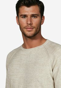 Hellbeige Sweatshirt aus einem strukturierten, weichen Stoff. Verfügt über einen Rundhalsausschnitt und Raglanärmel, und präsentiert ein einfaches und lässiges Design.