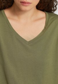Olijfgroene V-hals T-shirt met een zachte, gestructureerde stof en een relaxte pasvorm, met een soepele halslijn en minimale stikdetails.