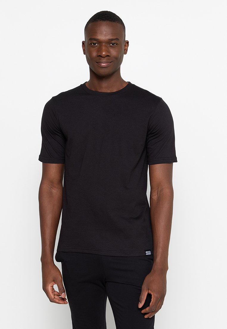 T-shirt noir à manches courtes en coton, avec un col rond et une étiquette logo en bas à gauche. Texture lisse et coupe ajustée.