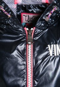 Chaqueta puffer navy con cremallera frontal y detalles en rosa, bordado con la letra "VIN" y un forro interior texturizado.