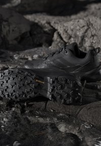 Chaussures de trail running noires avec semelles en caoutchouc Continental robustes reposant sur un terrain rocheux.