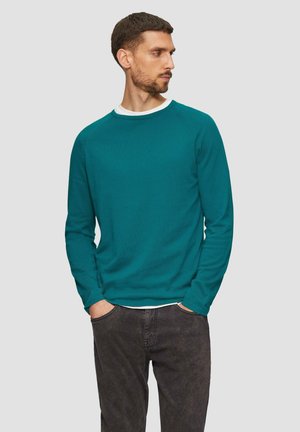 Teal trui met lange mouwen, een textuur oppervlak, ronde halslijn en raglanmouwen, gecombineerd met donkere spijkerbroek. Eenvoudig en functioneel ontwerp.