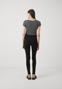 Leggings neri abbinati a una maglietta a maniche corte a righe bianche e nere, con un design aderente e una superficie liscia.