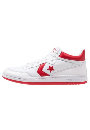 Biało-czerwone półwysokie trampki Converse z czerwonym logo gwiazdy i szewronu, białymi sznurowadłami oraz czerwonymi akcentami na podeszwie i kołnierzu.