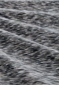 Tela negra y gris con un patrón texturizado y rayado. El material parece suave y ligero, mostrando sutiles variaciones de color.