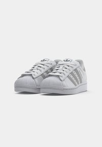 Pair of white Adidas Superstar sneakers with gray stripes and logo, front view on a white background.